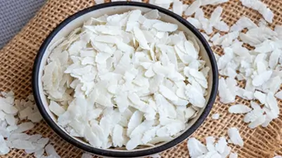 A bowl of uncooked flattened rice (poha) with scattered flattened rice on a jute tapestry, emphasizing Kirana King’s meticulous selection of premium-quality food grains, purity, and commitment to delivering trusted staples through careful sourcing and emphasis on superior grocery standards.